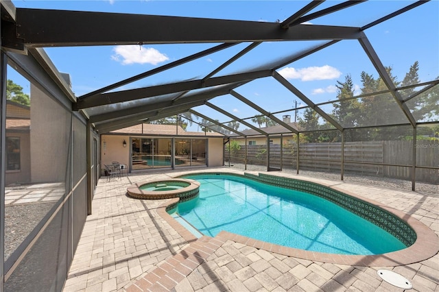 view of pool with glass enclosure, a pool with connected hot tub, a fenced backyard, and a patio area