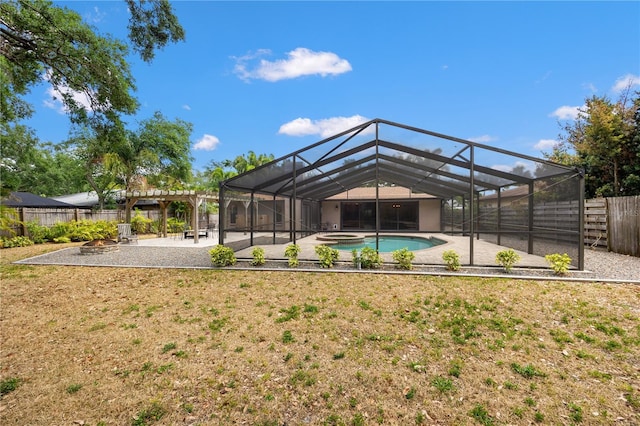 back of house with a pool with connected hot tub, a patio area, glass enclosure, a fenced backyard, and a yard