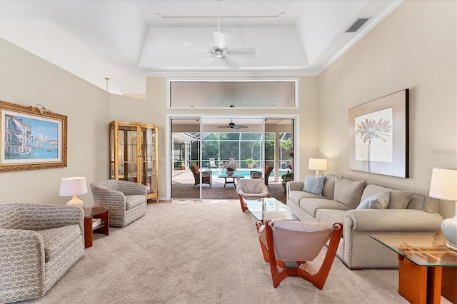 carpeted living area with a sunroom, ceiling fan, a raised ceiling, a towering ceiling, and ornamental molding