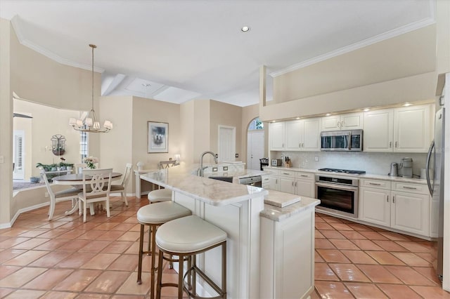 kitchen featuring stainless steel appliances, light tile patterned floors, ornamental molding, backsplash, and a sink