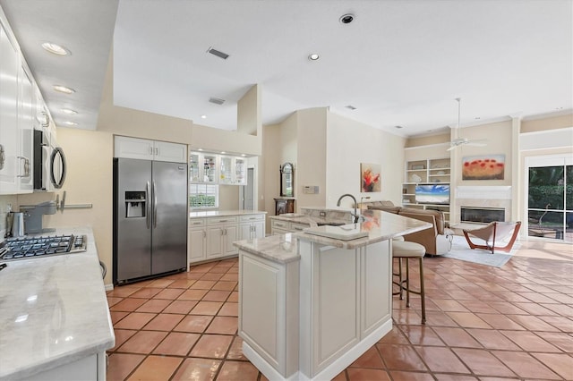 kitchen featuring appliances with stainless steel finishes, ceiling fan, a sink, white cabinetry, and light tile patterned floors
