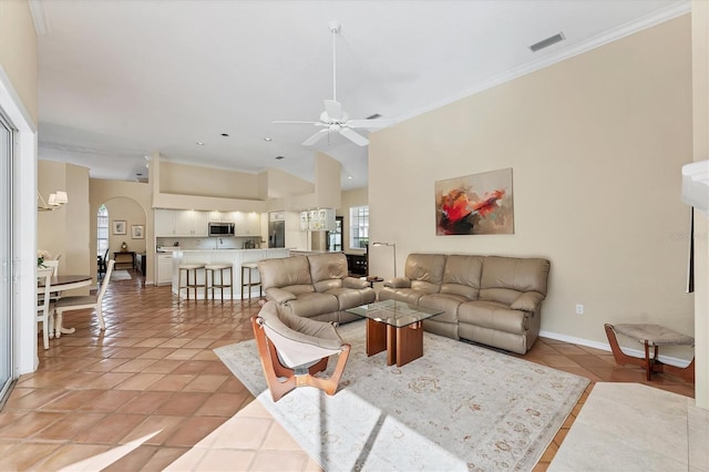 living area featuring ornamental molding, ceiling fan, light tile patterned floors, arched walkways, and baseboards