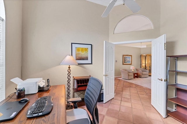 home office featuring ceiling fan, a high ceiling, and light tile patterned flooring