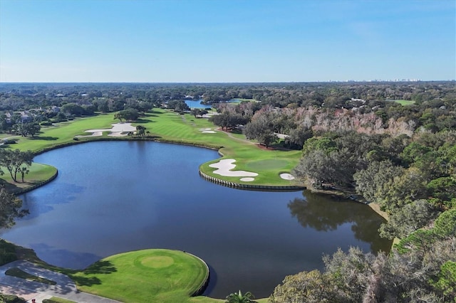 aerial view of a golf course, a large body of water, and a tree filled landscape