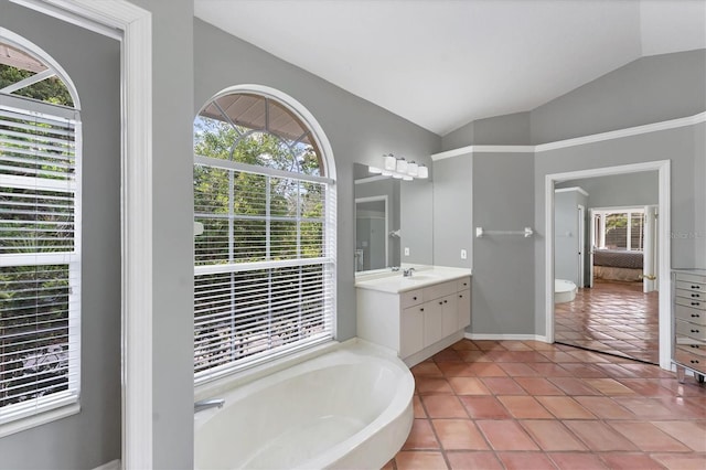 bathroom with lofted ceiling, a bath, vanity, baseboards, and tile patterned floors