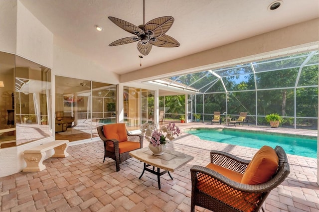 outdoor pool with a ceiling fan, a patio area, and glass enclosure