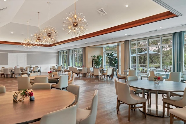 dining area featuring a raised ceiling, recessed lighting, plenty of natural light, a chandelier, and wood finished floors
