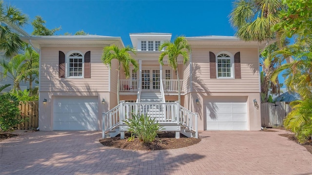 view of front of house featuring decorative driveway, a garage, stairs, and a porch