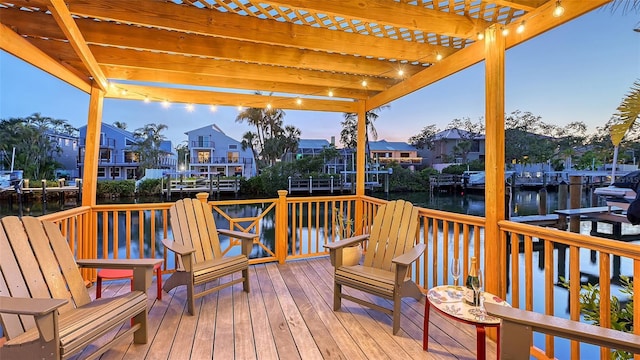 deck at dusk with a residential view, a pergola, and a water view