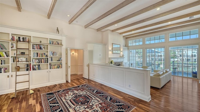 interior space with a fireplace, beamed ceiling, and dark wood-style flooring