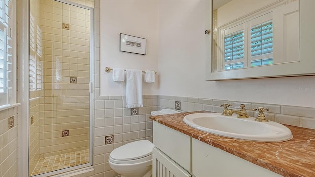 bathroom with vanity, toilet, a wainscoted wall, tile walls, and a stall shower