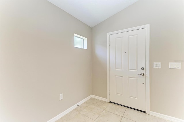 doorway with light tile patterned flooring, lofted ceiling, and baseboards