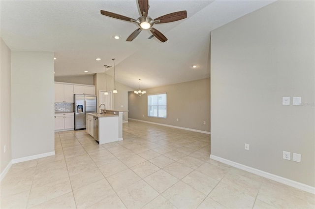 kitchen featuring lofted ceiling, white cabinets, stainless steel appliances, open floor plan, and ceiling fan with notable chandelier