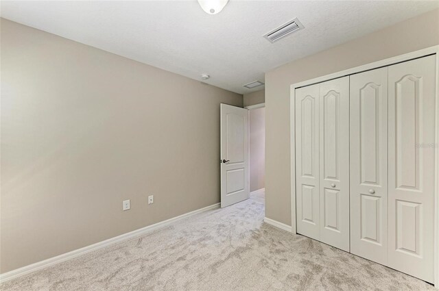 unfurnished bedroom with visible vents, a closet, baseboards, and carpet floors