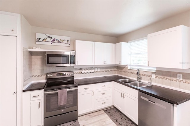 104 Shoreland Dr, Osprey, FL 34229 - kitchen with dark countertops, appliances with stainless steel finishes, a sink, and white cabinetry