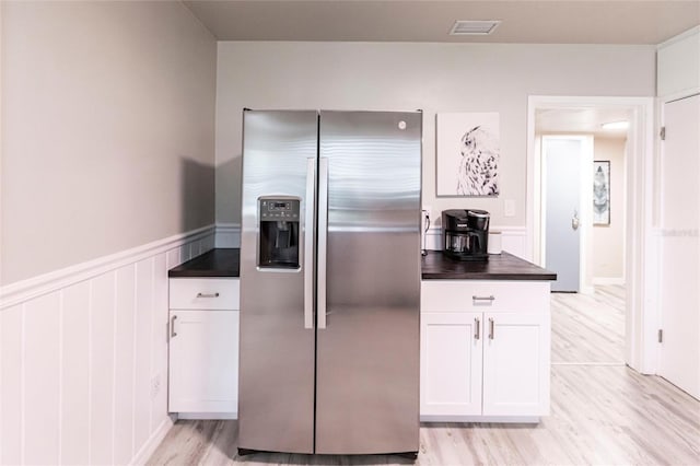 104 Shoreland Dr, Osprey, FL 34229 - kitchen featuring dark countertops, light wood-type flooring, stainless steel refrigerator with ice dispenser, white cabinetry, and visible vents