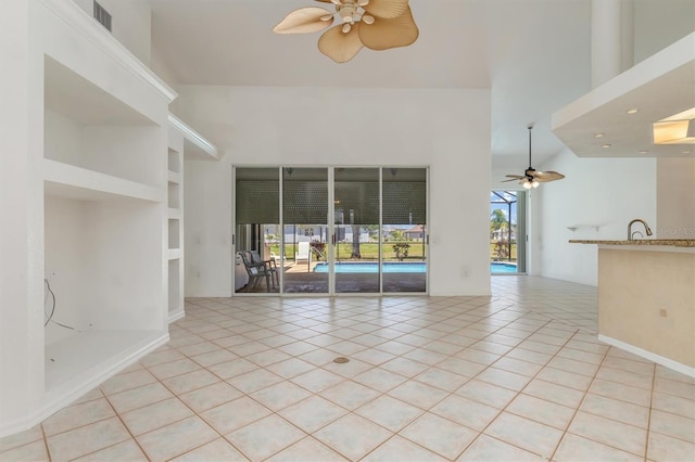 unfurnished living room with a ceiling fan, visible vents, built in features, and light tile patterned flooring