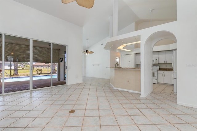 unfurnished living room with a high ceiling, ceiling fan, and light tile patterned floors