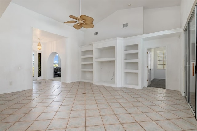 unfurnished living room with light tile patterned floors, visible vents, arched walkways, and ceiling fan