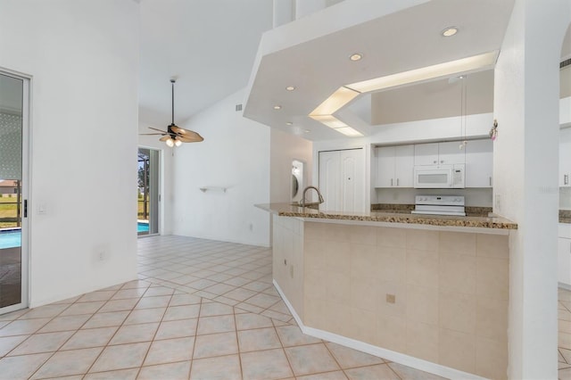 kitchen with white cabinets, a wealth of natural light, white microwave, and stove