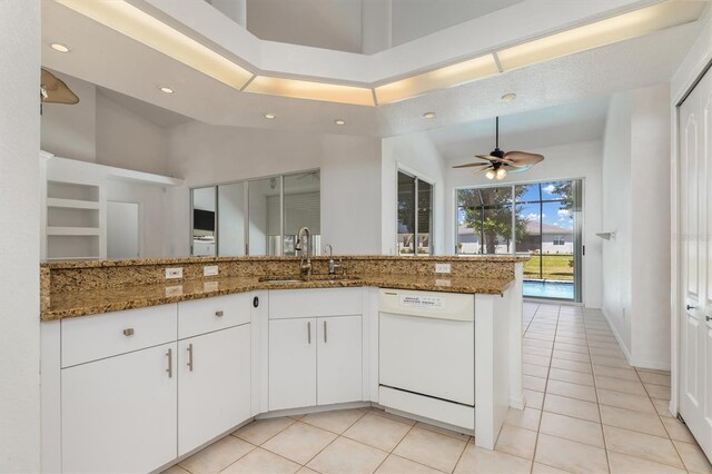 kitchen with dishwasher, stone countertops, light tile patterned floors, and a sink