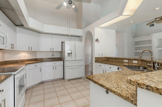 kitchen featuring arched walkways, a ceiling fan, white appliances, and a sink