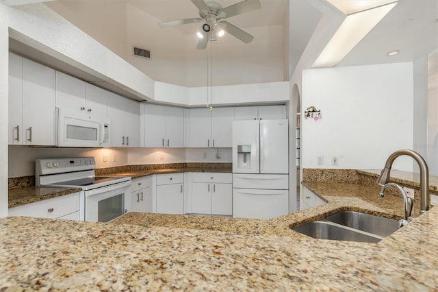 kitchen with a sink, white appliances, ceiling fan, light stone countertops, and visible vents