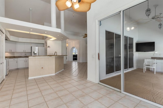 kitchen with a ceiling fan, arched walkways, fridge with ice dispenser, and light tile patterned flooring