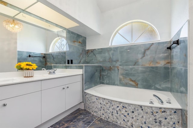 full bath with plenty of natural light, vanity, a washtub, and marble finish floor