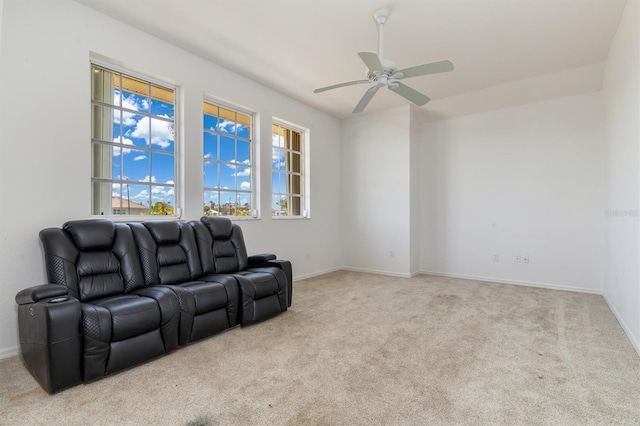 carpeted living area with a ceiling fan and baseboards