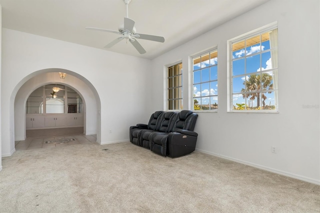unfurnished room featuring arched walkways, carpet, a ceiling fan, and baseboards
