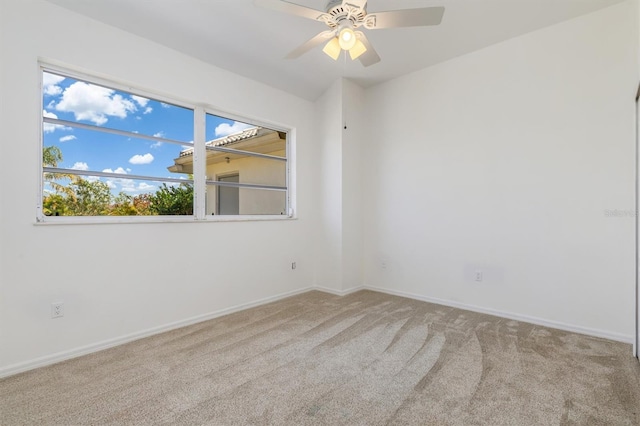 carpeted spare room with baseboards, a ceiling fan, and plenty of natural light