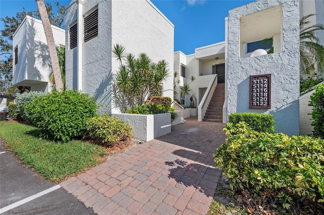 view of side of property featuring stucco siding and stairs
