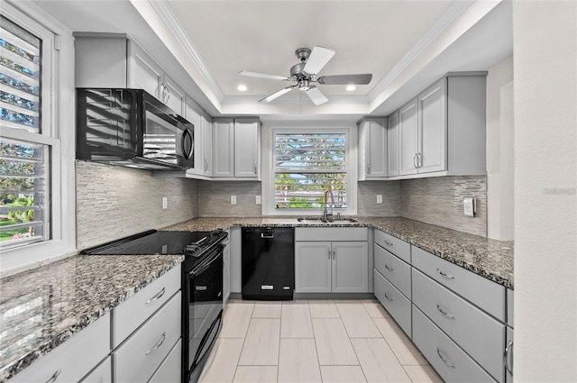 kitchen featuring dark stone counters, black appliances, a ceiling fan, and a sink