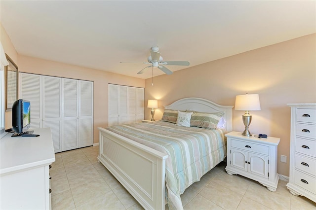bedroom with light tile patterned floors, ceiling fan, baseboards, and two closets
