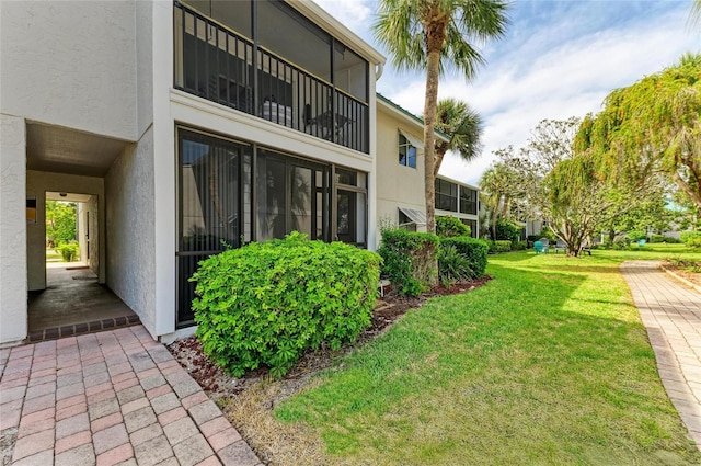 view of side of home with a lawn and stucco siding