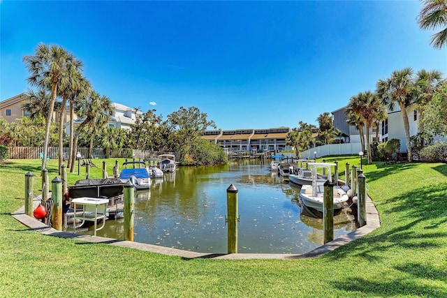 view of dock with fence, a yard, and a water view
