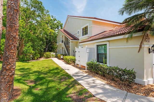 7639 Fairway Woods Dr Unit 605, Sarasota, FL 34238 - view of side of home featuring a yard, a tiled roof, stucco siding, and fence