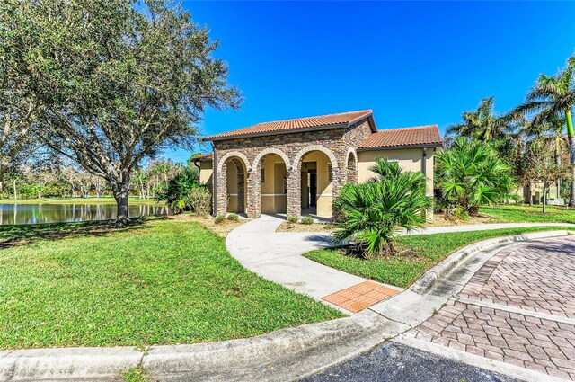 2084 La Palma Ave, Port Charlotte, FL 33953 - mediterranean / spanish-style home with a tiled roof, a front lawn, stone siding, a water view, and stucco siding