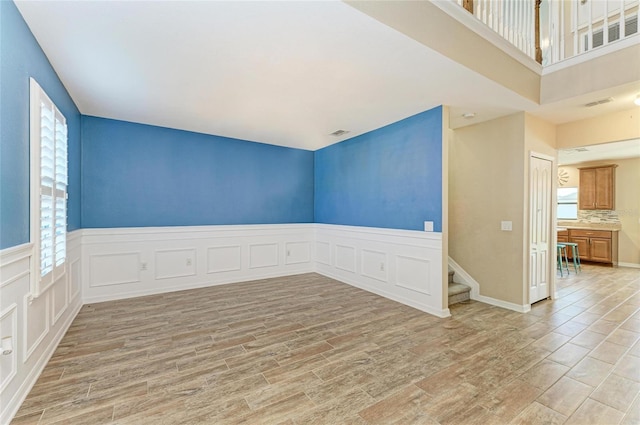 2084 La Palma Ave, Port Charlotte, FL 33953 - empty room featuring light wood-style flooring, stairs, a wainscoted wall, and a decorative wall