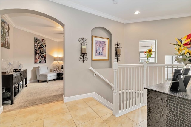 interior space featuring carpet floors, ornamental molding, baseboards, tile patterned floors, and arched walkways
