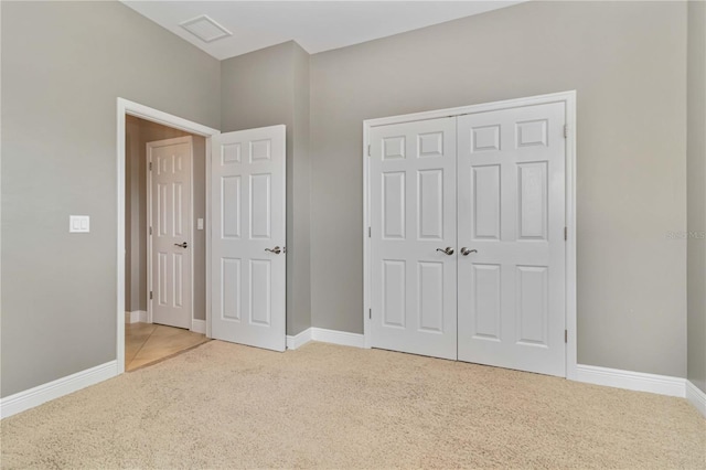 unfurnished bedroom with light colored carpet, baseboards, visible vents, and a closet