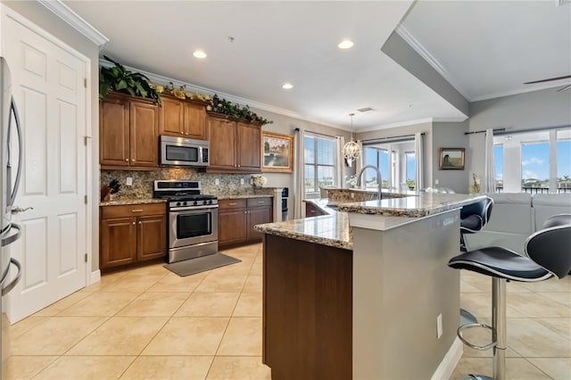 kitchen featuring plenty of natural light, a breakfast bar area, appliances with stainless steel finishes, a sink, and light tile patterned flooring