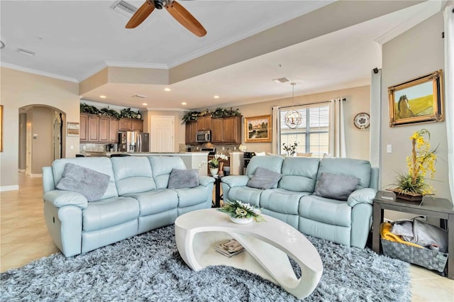 living room featuring visible vents, ornamental molding, arched walkways, ceiling fan with notable chandelier, and light tile patterned floors