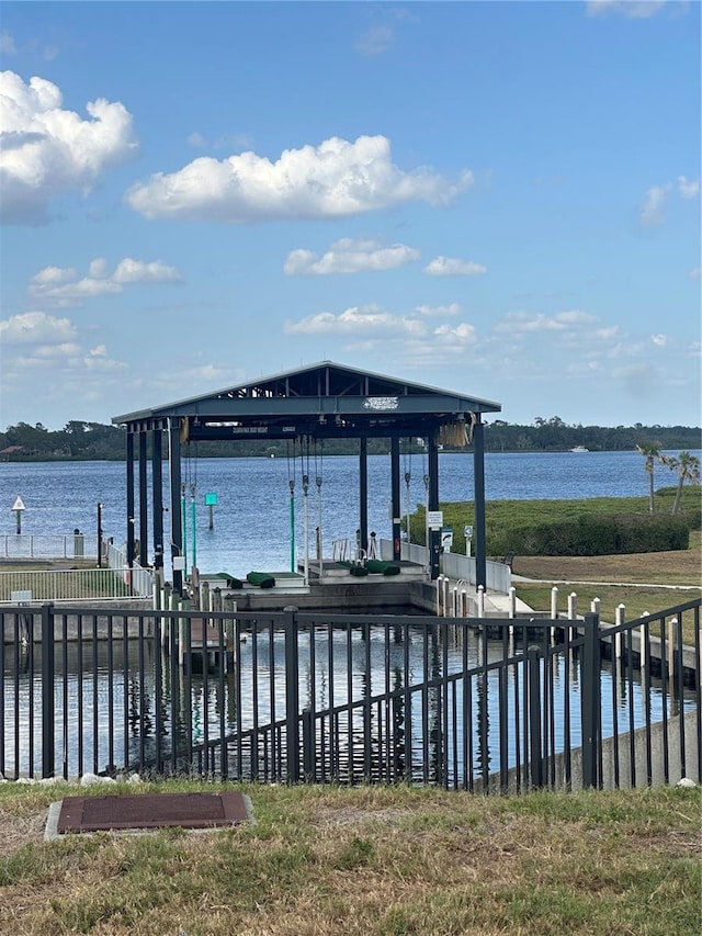 view of dock featuring fence, boat lift, and a water view