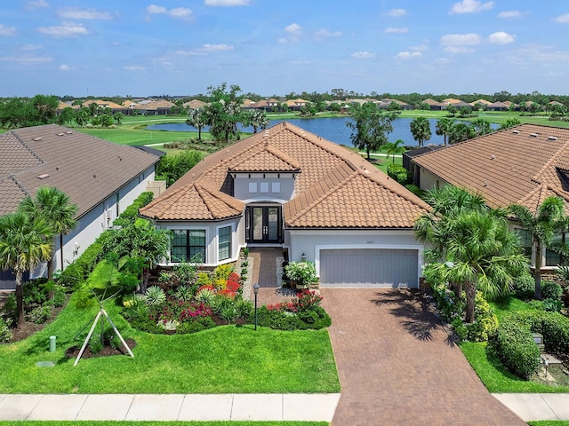 15037 Montello Way, Lakewood Ranch, FL 34211 - mediterranean / spanish home with a front lawn, a water view, decorative driveway, a tiled roof, and an attached garage