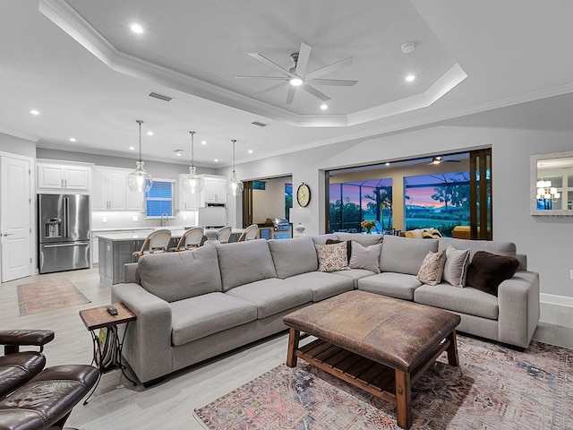 15037 Montello Way, Lakewood Ranch, FL 34211 - living area featuring a raised ceiling, a ceiling fan, visible vents, light wood-style flooring, and ornamental molding