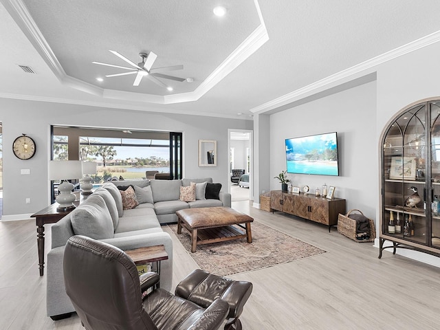 15037 Montello Way, Lakewood Ranch, FL 34211 - living room featuring ceiling fan, light wood-type flooring, a tray ceiling, ornamental molding, and a textured ceiling