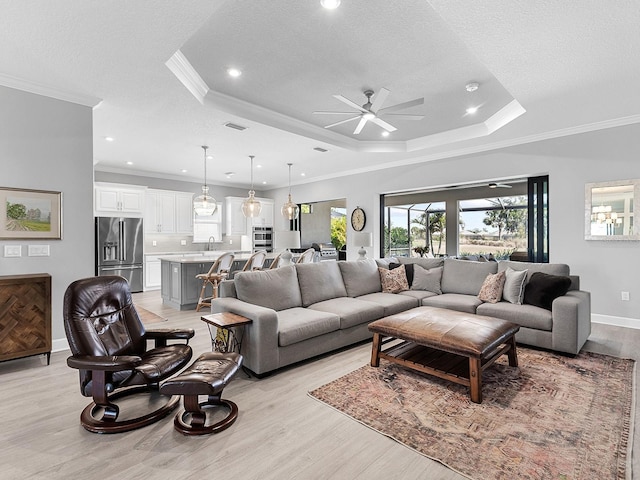 15037 Montello Way, Lakewood Ranch, FL 34211 - living room with crown molding, ceiling fan, a tray ceiling, baseboards, and light wood-type flooring