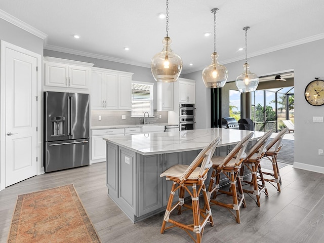 15037 Montello Way, Lakewood Ranch, FL 34211 - kitchen with a sink, appliances with stainless steel finishes, decorative backsplash, and light wood-style floors